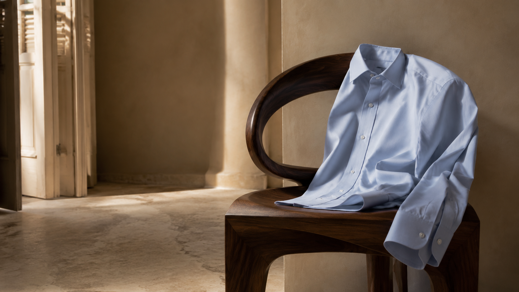 A light blue Italian shirt prepared on a walnut chair in warm Roman light